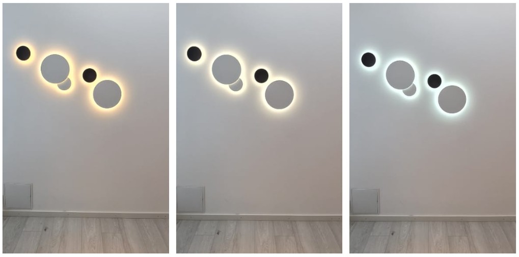 Kolme pyöreää seinävalaisinta rivissä loistavat lämpimän, hyväin ja viileän sävyisinä valkoista seinää vasten – täydellinen ratkaisu tunnelmallisen moderniin luomiseen LedStore.fi:n laadukkailla led-valaistusratkaisuilla. - LedStore Round Eclipse wall lights grouped in a series of five fixtures. There are two sizes of the light and two of the lights overlap each others.
