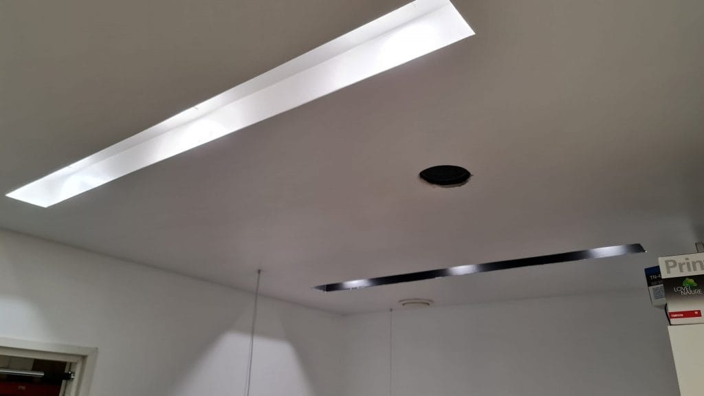 6. Musta ja valkoinen Ura valmiina - LedStore Kattonäkymä kahdella upotettavalla LED-valolla, pyöreällä keskikaiuttimella/tuulettimella ja "Print"-kyltillä oviaukon lähellä valkoisilla seinillä oikeassa alakulmassa.