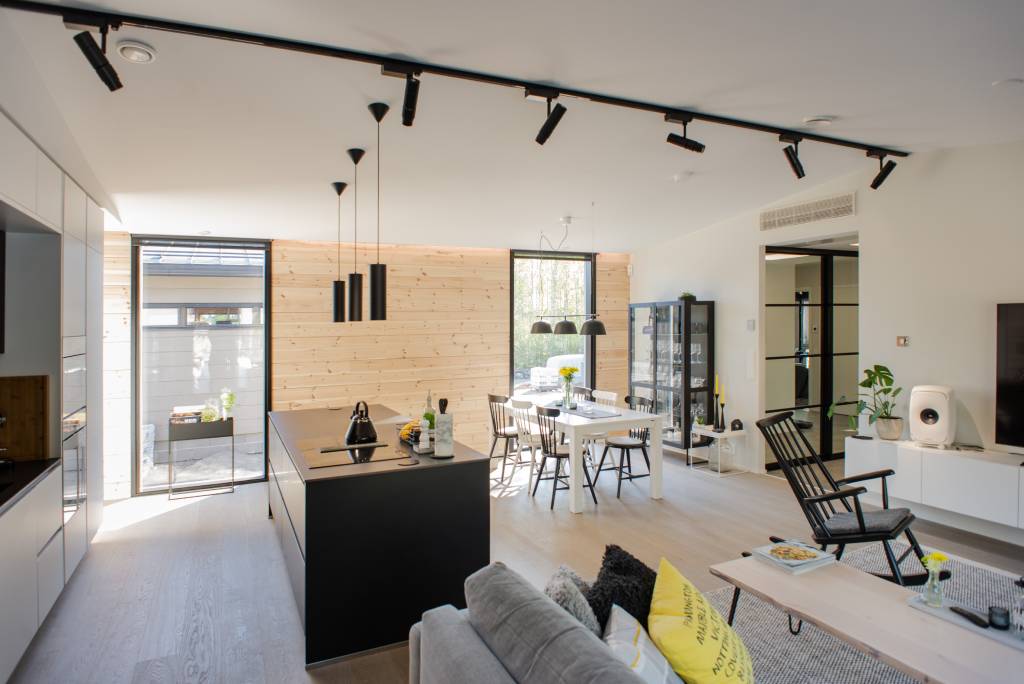 Picture 1 Living room-kitchen - LedStore Modern open-concept living space with light wood floors, kitchen island, dining table, black LED fixtures, large windows, white walls for bright airy feel.