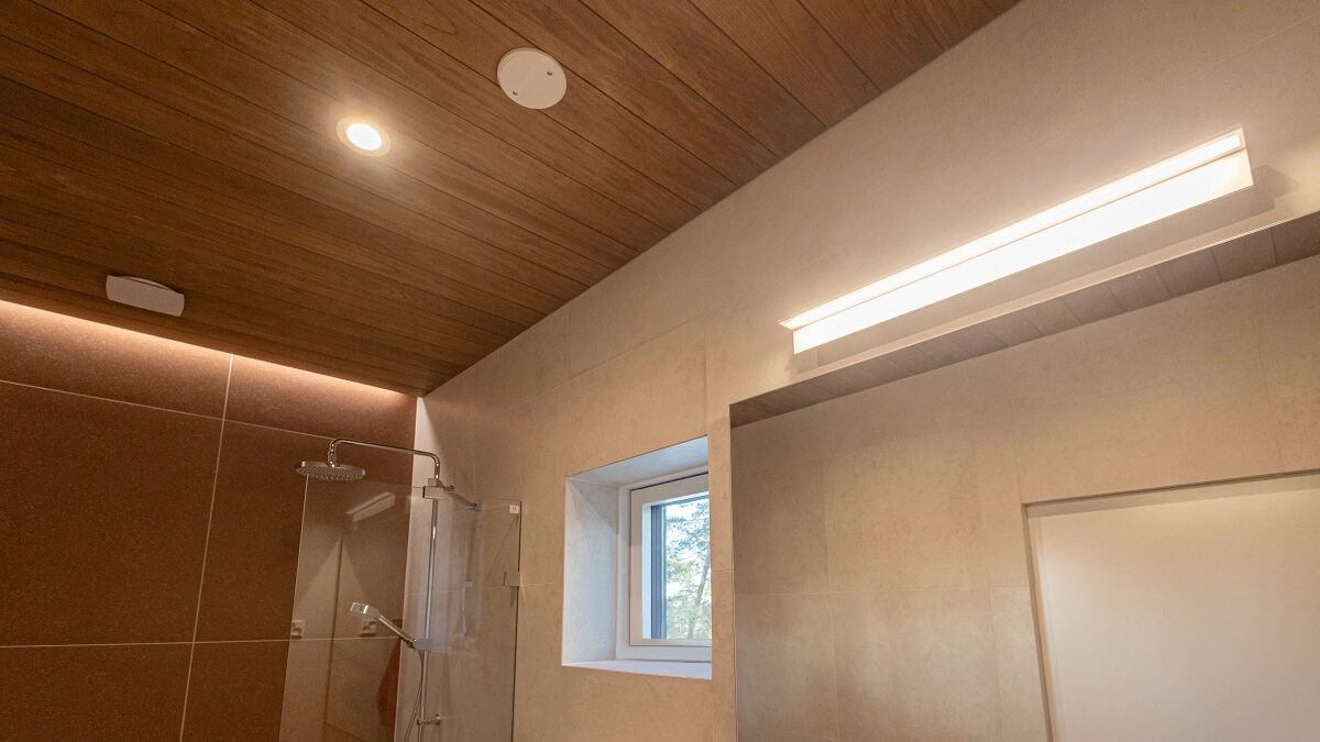 Moderni kylpyhuone, jossa puukatot, beiget seinät, suihku ja ikkuna. Kirkas LED-yleisvalaistus LedStore.fi:ltä.