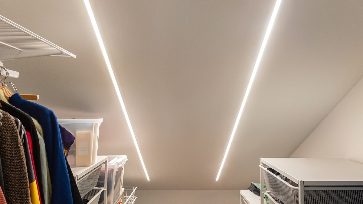 Vaatehuoneen katossa kaksi kirkasta LED-listaa LedStore.fi:ltä, valaisten vaatteet ja säilytyslaatikot molemmin puolin.