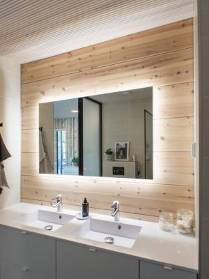 Spotlight in the bathroom-LedStore - LedStore LedStore.fi tarjoaa moderniin kylpyhuoneeseen täydellisen valaistusratkaisun. Tyylikäs LED-taustavalaistu peili, jota kehystävät elegantit puupaneelit, luo tilaan ylellisen tunnelman. Peilin alla on kaksi valkoista allasta, joissa on kromiset hanat ja elegantti työtaso. Seinällä sijaitsevat pyyhekoukut lisäävät käytännöllisyyttä, ja peilistä heijastuvat koriste-esineet viimeistelevät kokonaisuuden.