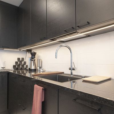 LED lighting in the kitchen highlights the black cabinets and chrome sink and enhances the lighting in the modern workspace.