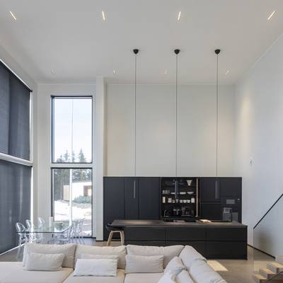 Modern kitchen lighting with pendant lights, natural light from large windows, ambient and accent LEDs.