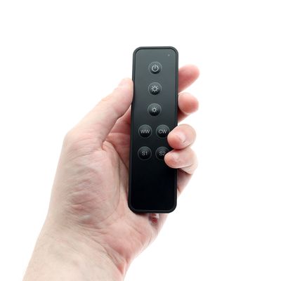 Stylish black remote control with 7 buttons for LED lighting systems, held in the hand for easy use. Perfect for modern lighting solutions.