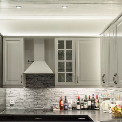Kitchen with white cabinets and LED strip lighting above and below the upper kitchen cabinets.