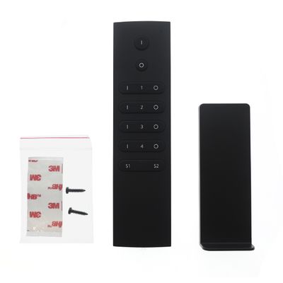 Alternative text: 'Black remote control with wall mount, screws and tape for LED lighting installation with white background.