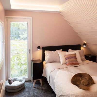 Bedroom lighting in a sloping ceiling with a LED strip light in a drop-down clip, wall lights on both sides of the bed.