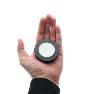 Hand-held circular LED controller, black and white design, white background, lighting technology.