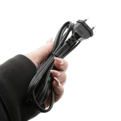 Close-up of a hand holding a twisted black electrical wire with a two-pronged plug, insulated with a white background for LED lighting solutions.