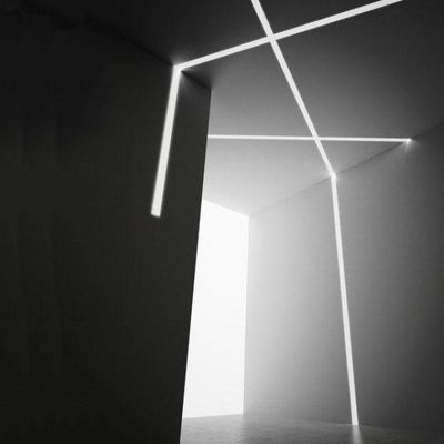 A dark minimalist room illuminated by intersecting white LED lines on the walls and ceiling, forming an abstract geometric light pattern.