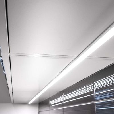 Modern minimalist white ceiling with long narrow bright LED lighting; horizontal lines on the adjacent glass wall in the background.