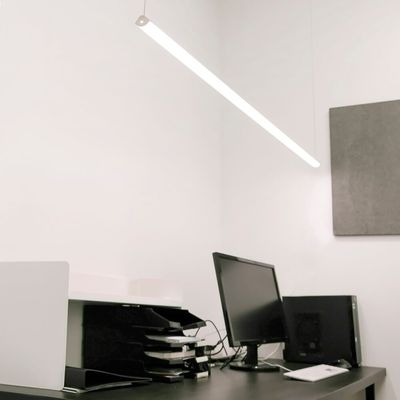 Modern office environment with energy-efficient LED overhead lighting, sleek black desk, computer monitor and organised paper trays.