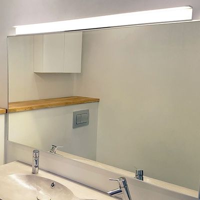 Bathroom with LED-lit mirror, modern sink and taps, wooden shelf and white cabinets. The ideal lighting solution from LED lighting shop.