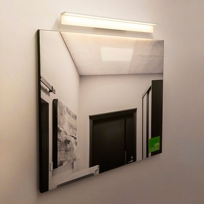 Alternative text: a modern hallway with white walls, a dark door and an LED luminaire reflecting from the mirror creates a contemporary LED lighting atmosphere.