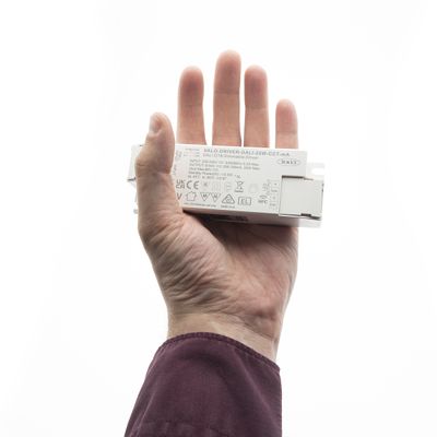 Alternative text: hand holding a white LED lighting control with symbols against a clear background, highlighting the technical innovation of LED lighting solutions.
