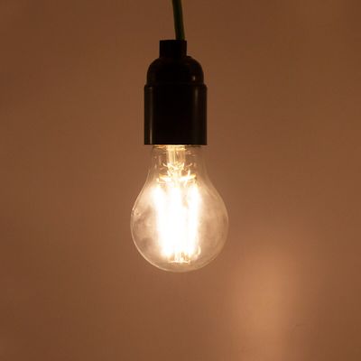 A cord-hanging LED lamp emits a soft glow against a neutral background, showcasing modern energy-efficient lighting solutions.