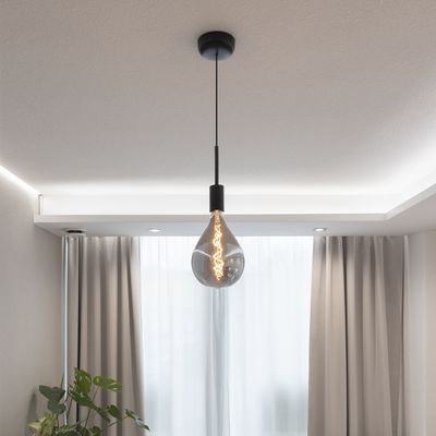 A pendant light with Edison bulb and black lamp illuminates the room with light curtains and creates a warm atmosphere.