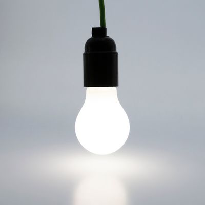 LED lamp hanging on a green wire illuminates a plain background. Perfect for energy efficient lighting solutions.