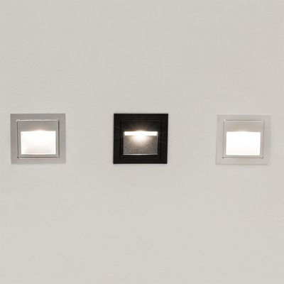 Alternative text: 'Three recessed wall lights: two white and one black, illuminated on a plain background for LED lighting company SEO.