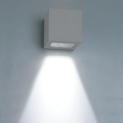 The cube-shaped LED wall light illuminates a bright, downward beam on a soft blue wall and accentuates modern interiors with energy-efficient lighting.