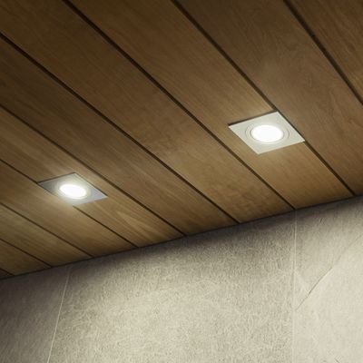Alternative text: 'Wooden ceiling with recessed LED lights illuminating a textured grey wall in a modern lighting store