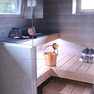 Modern sauna interior with wooden benches, glass door, copper water tank on the floor and heater stones in the corner. Ideal for improving LED lighting.