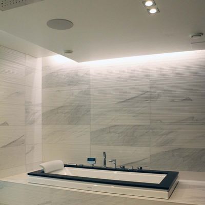 Modern bathroom with marble tiles, rectangular bathtub and recessed LED ceiling lights