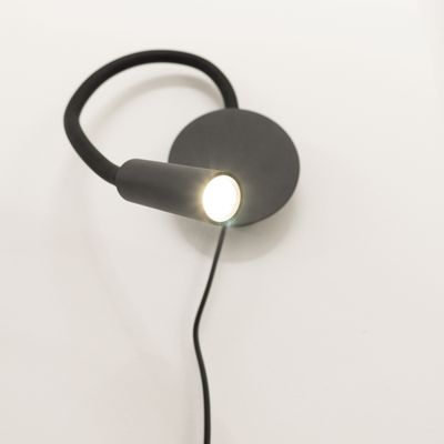 Modern black wall mounted reading light with flexible stem and round top, set against a white background with stylish LED lighting.