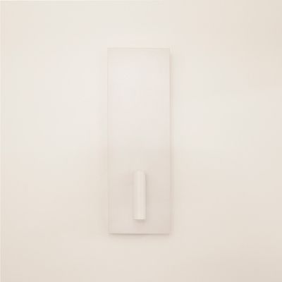 Minimalist white wall sculpture with rectangular base and central cylindrical projection, illuminated by LED lighting to enhance the attractiveness of the design.