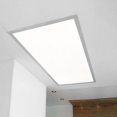 Bright rectangular LED ceiling light panel on a white ceiling; brown wooden accent appears in the corner for a contemporary interior.