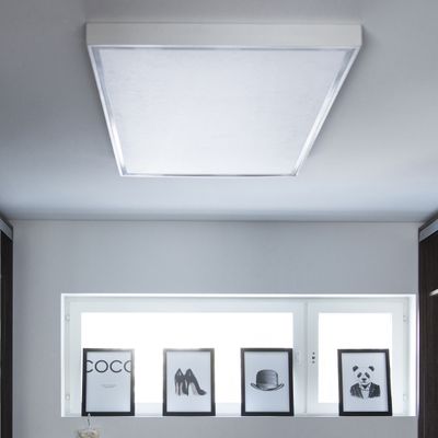 Ceiling LED luminaire illuminates monochrome framed images of text, shoes, hat and panda on a shelf next to a window in a modern home interior.