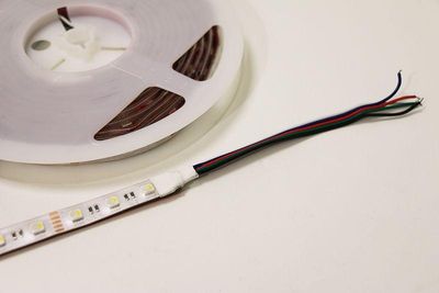 LED strip lights with red, green and black wires on a white surface for home decoration, cabinet lighting, energy efficient solutions.