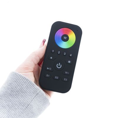 Close-up of a hand-held, stylish black LED photo remote control with a vivid colour wheel and several function buttons on a white background.