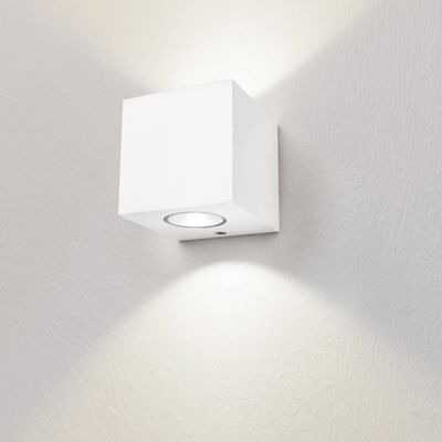 A minimalist white cube wall light illuminates a softly textured white wall with upward and downward light. Perfect for modern LED lighting.