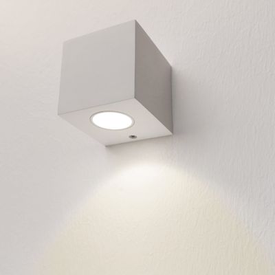 Alternative text: cube-shaped LED wall light illuminates soft white light on a textured wall, a modern lighting design for your home or office.