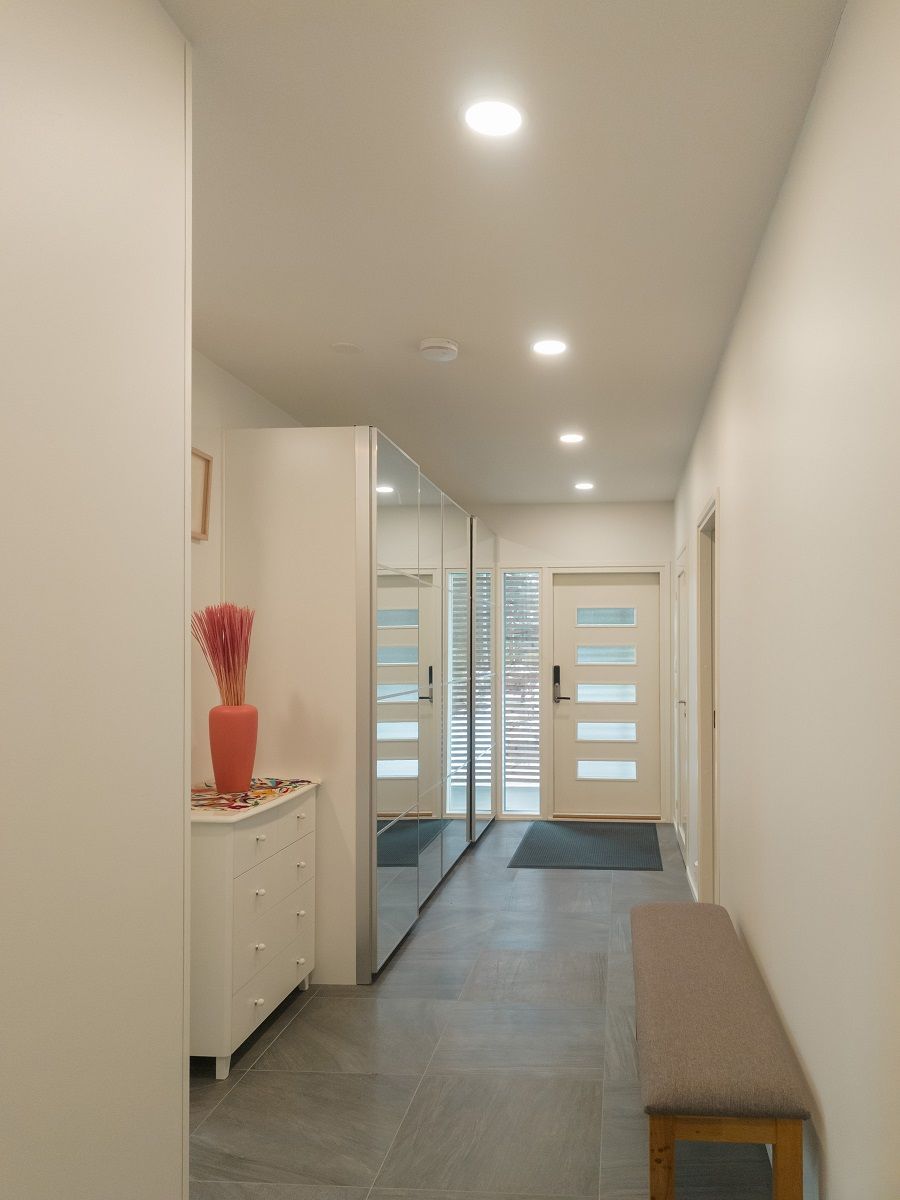 The light hallway is illuminated by small round panel lamps.