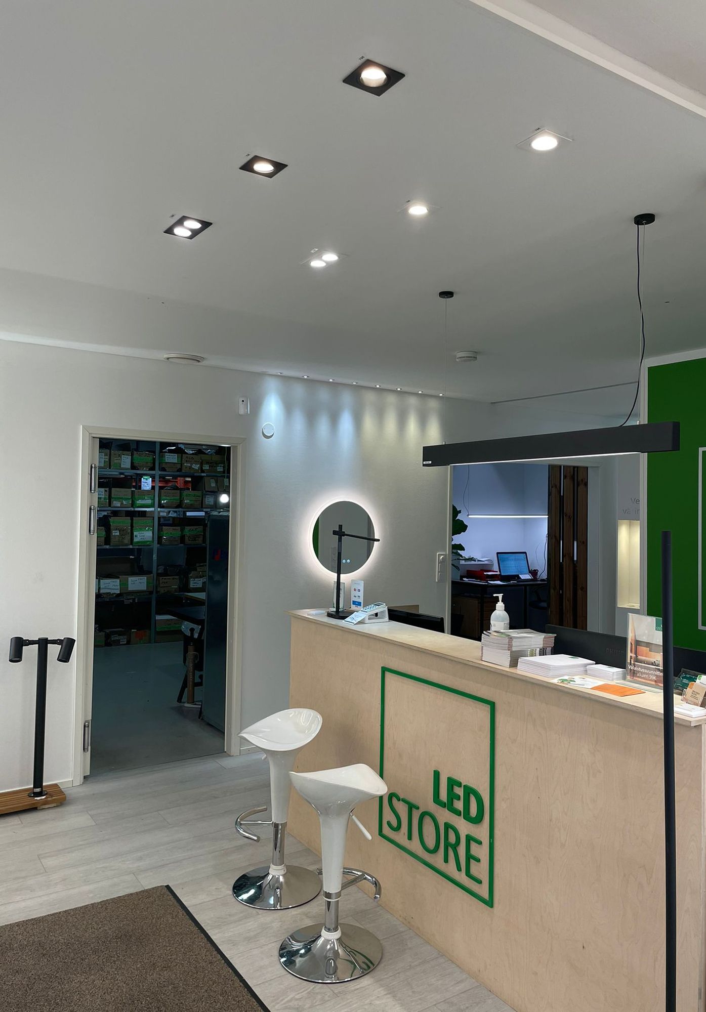 Led lights at Ledstore\'s showroom. Spots on the ceiling in front of the counter and a VIIVA ceiling light above the counter. The wall is accented by 3W spot sets, fixed and directional. Moon 600 light mirror under the spots. Ledstore.fi
