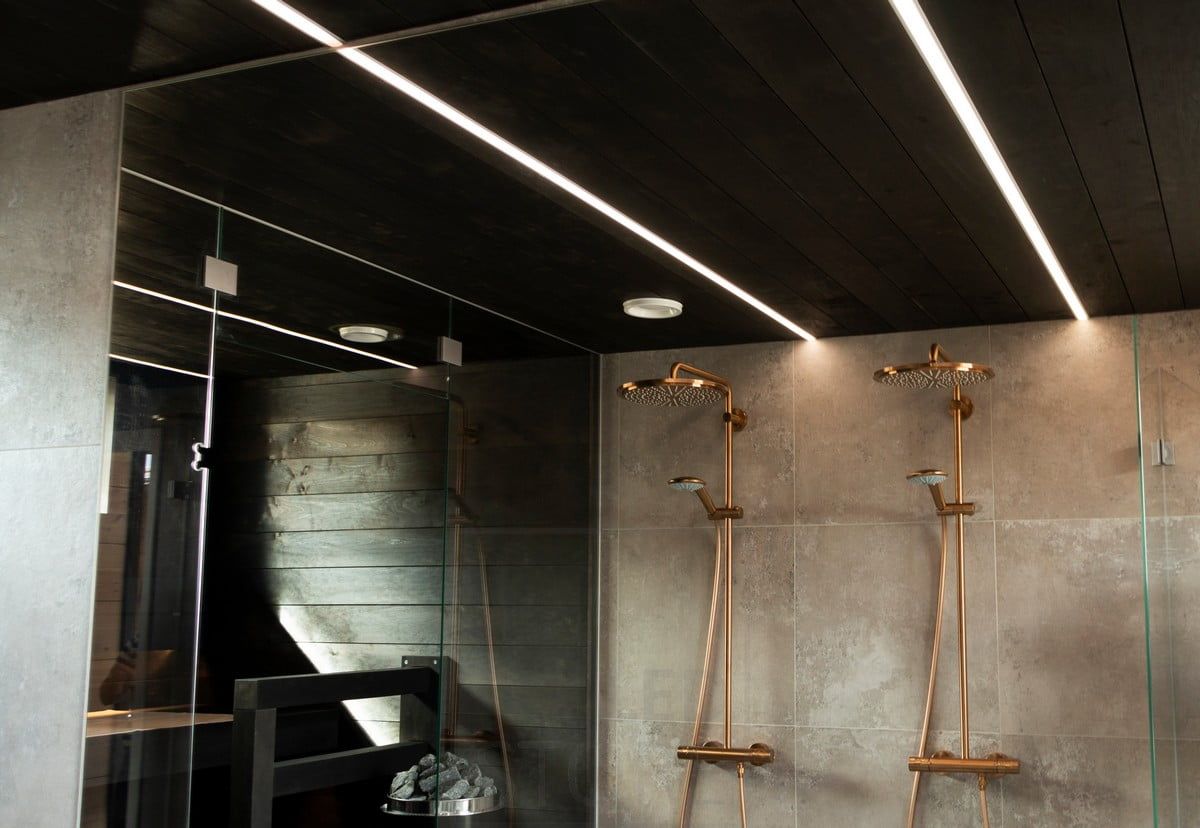 Housing Fair 2020: led strips illuminating the bathroom in narrow recessed profiles in the black ceiling of the washroom. The light lines illuminate the space with high quality and pleasant light. Ledstore.fi