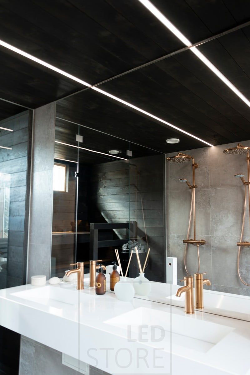 Housing Fair 2020: led strips illuminating the bathroom in narrow recessed profiles in the black ceiling of the washroom. The lighting is creating beautiful lines of light in the ceiling. Ledstore.fi