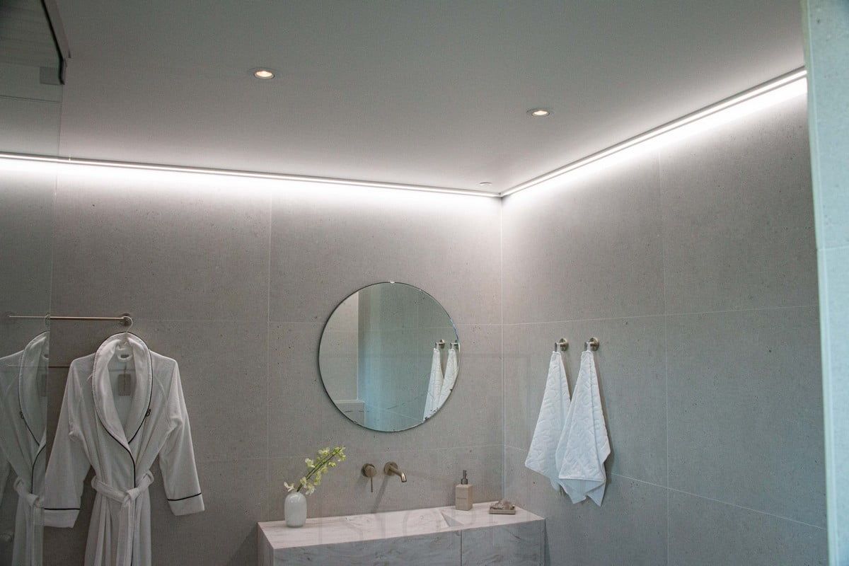 Housing Fair 2022: Led strip mounted on a low-profile surface, on the ceiling next to the wall, providing soft, indirect light for the bathroom. Ledstore.fi