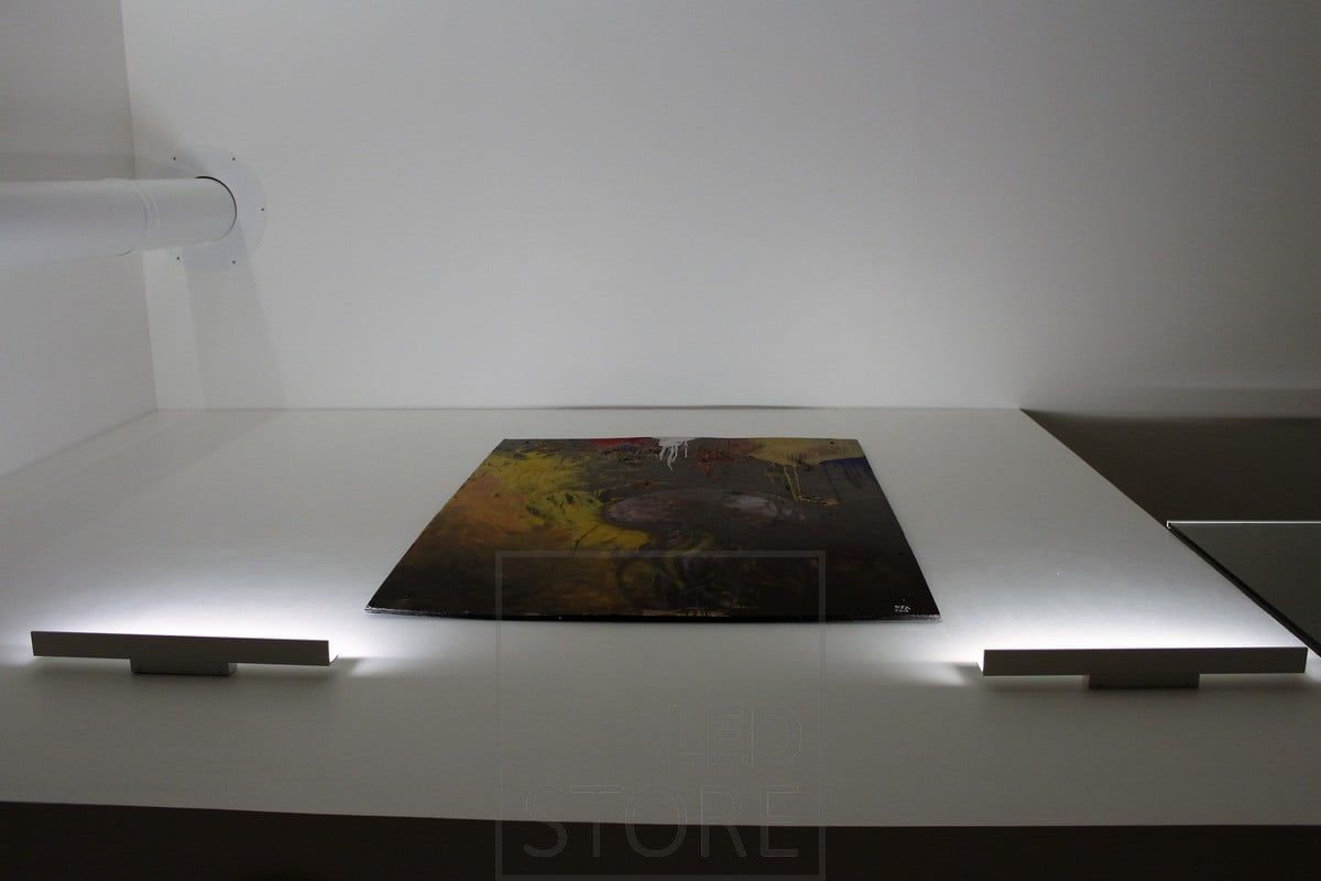 Blade wall light illuminating from the bottom up and highlighting the artwork with indirect light. Ledstore.fi