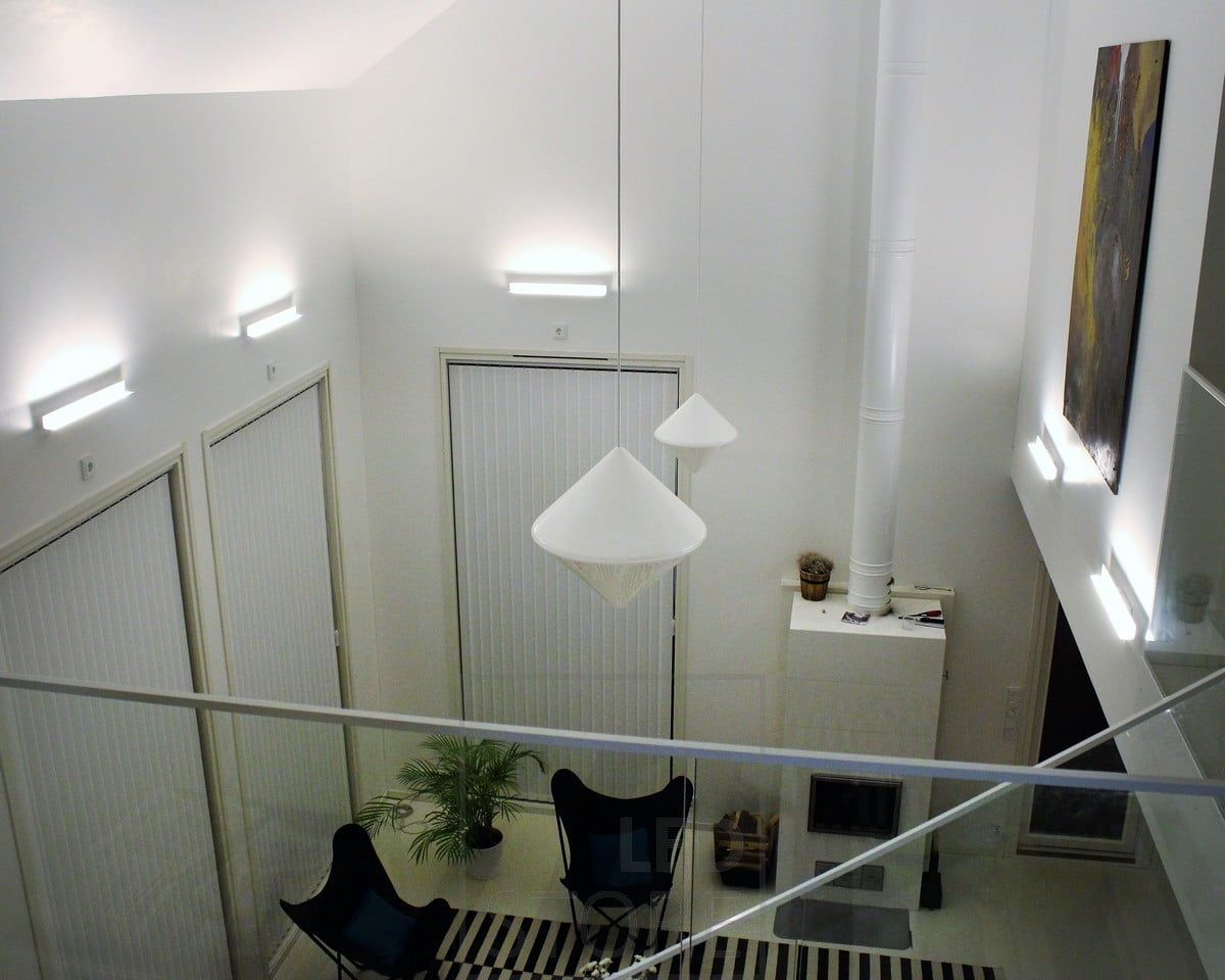 A living room with atmospheric indirect lighting created with Led BLADE wall lamps. The luminaire is mounted to illuminate from the bottom up, and thus the indirect lighting also emphasises the height of the space and the artwork on the wall. Ledstore.fi
