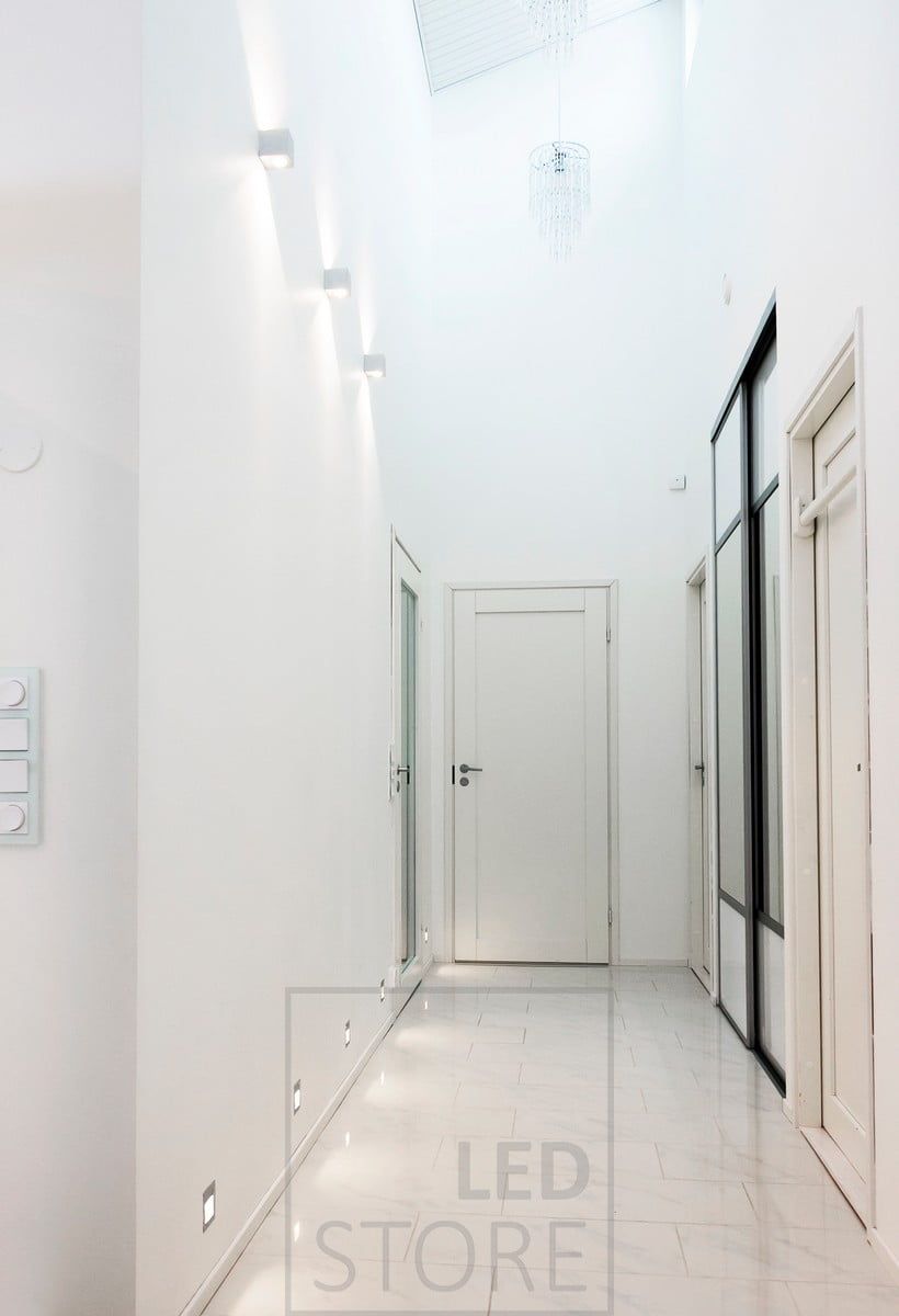 CUBIC led wall luminaire illuminating in two directions in a corridor to emphasize the height of the space. Recessed led wall lights on the floor border provide indirect light to the floor. Ledstore.fi