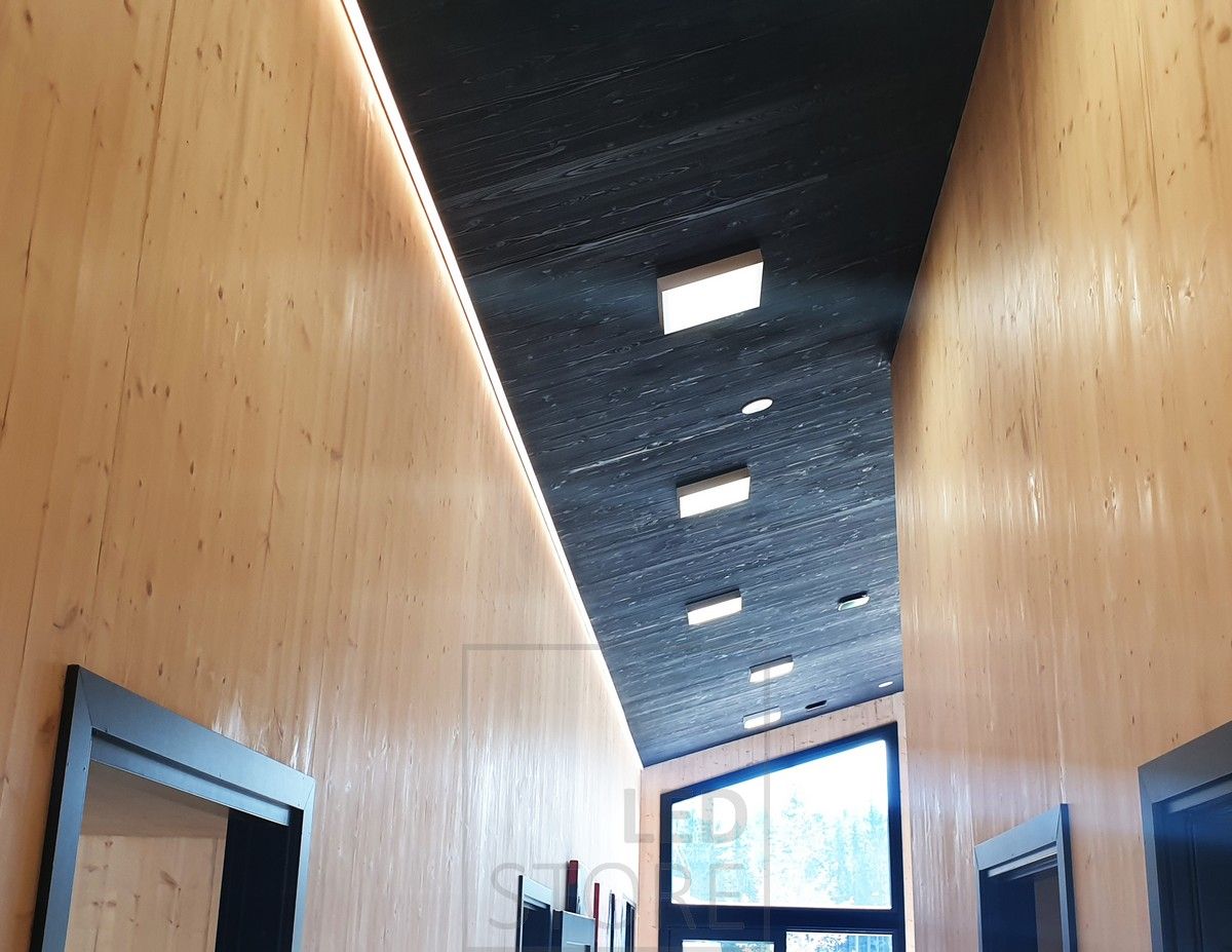 In a high corridor, an LED strip between the ceiling and the wall provides mood lighting. General lighting with panel lights. Ledstore.fi