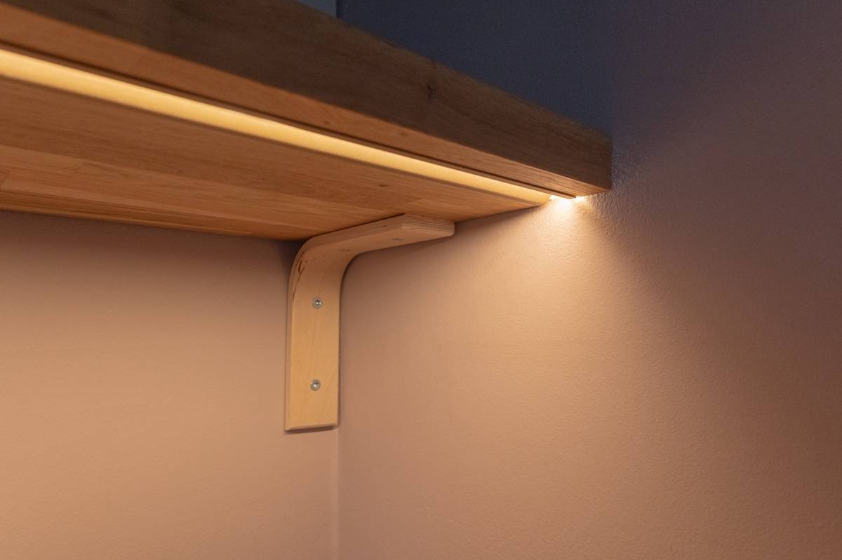 Close-up of a profile flush-mounted in the bottom of a shelf. The colour of the profile is matte copper.