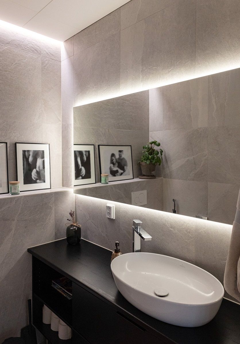 LED strip light embedded between wall and ceiling and behind mirror.