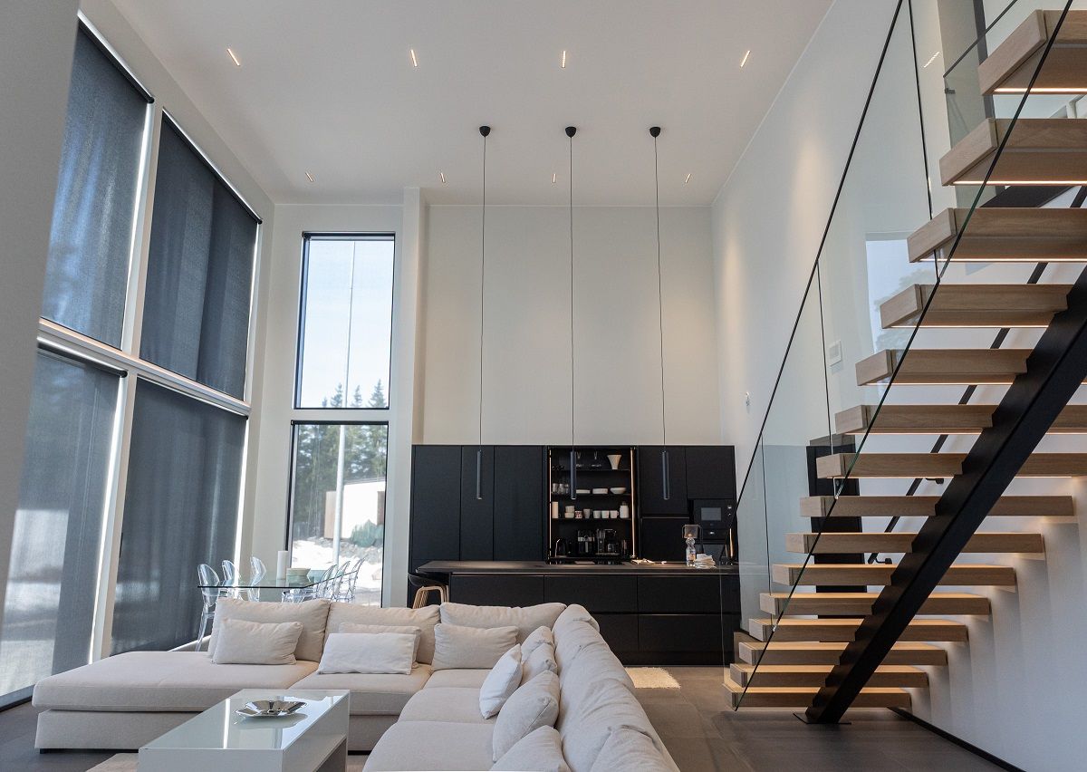 LINJA10 spotlights for general lighting in the high ceiling of the living room, kitchen and dining area, and three LED PIIPPU 2.0 pendant lights above the kitchen island. LED strip on the stair treads.