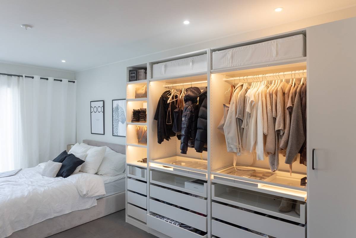 Bedroom with round spotlights and wardrobe illuminated with LED strip.
