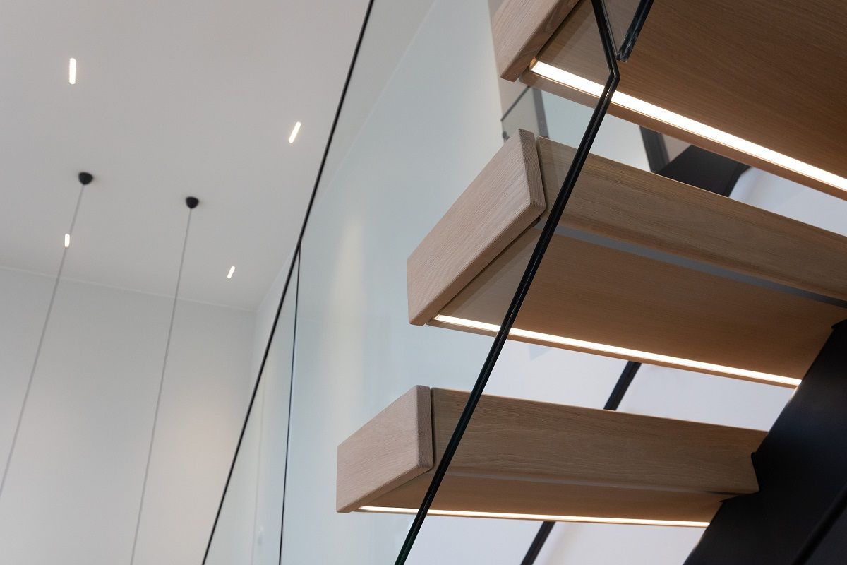 Under the stair tread, flush mounted led strip in profile. LINJA10 led spots in the background on the ceiling.